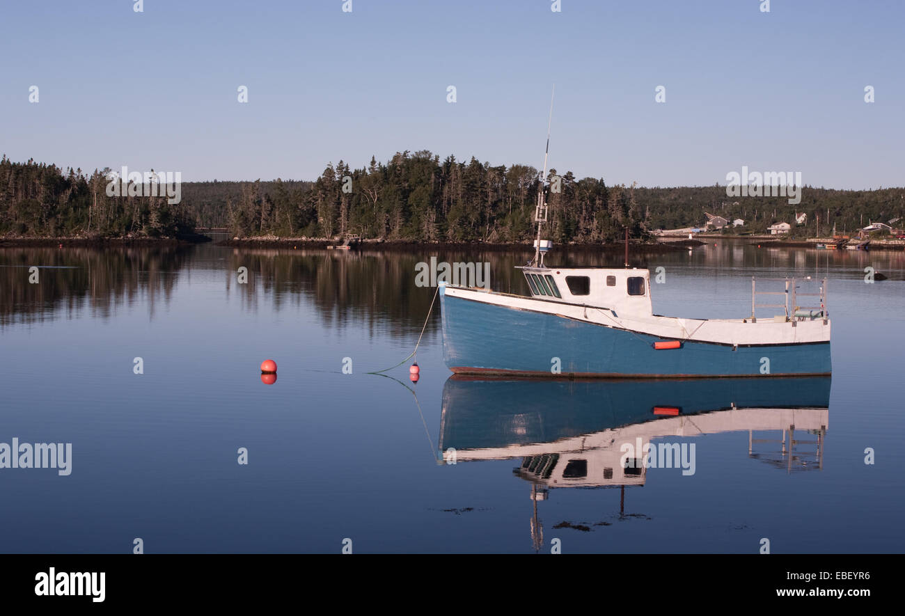 Blue and white fishing boat anchored on calm water Stock Photo - Alamy