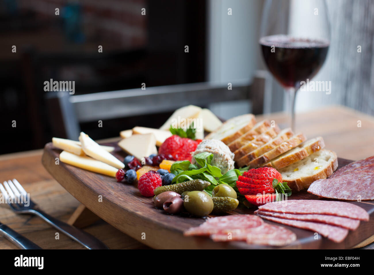 Cheese and Fruits Assortment on Cutting Board with Red, White Wine on  Wooden Background. Stock Photo by annapustynnikova