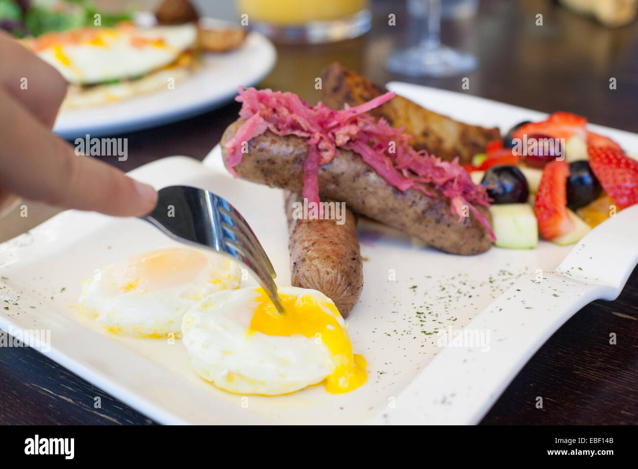 Hand with fork breaking out an egg yoke Stock Photo