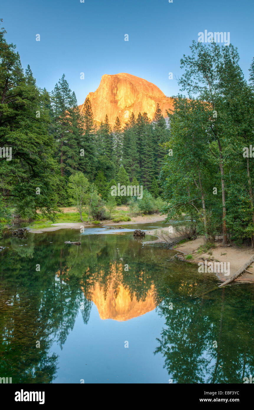 The sunsetting on Half Dome, seen reflecting in the Merced River in Yosemite National Park Stock Photo