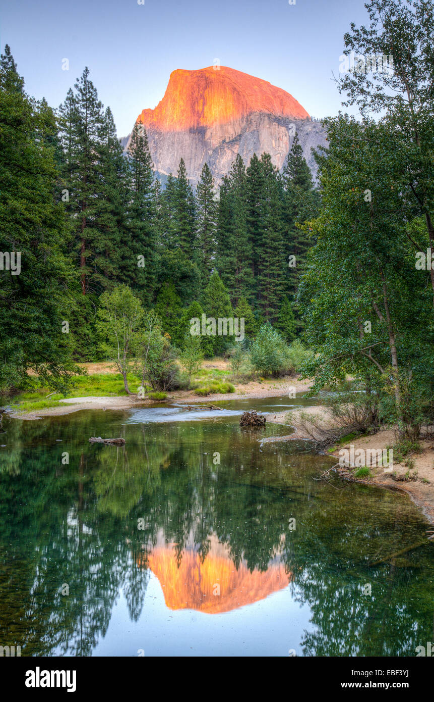 The sunsetting on Half Dome, seen reflecting in the Merced River in Yosemite National Park Stock Photo
