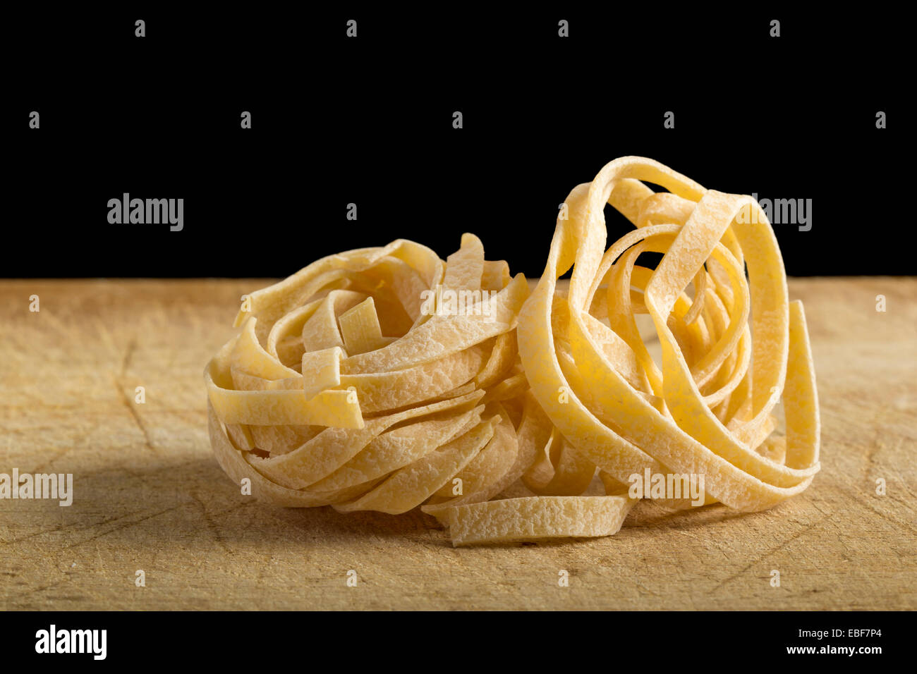 Homemade tagliatelle on the wooden table with black background Stock Photo