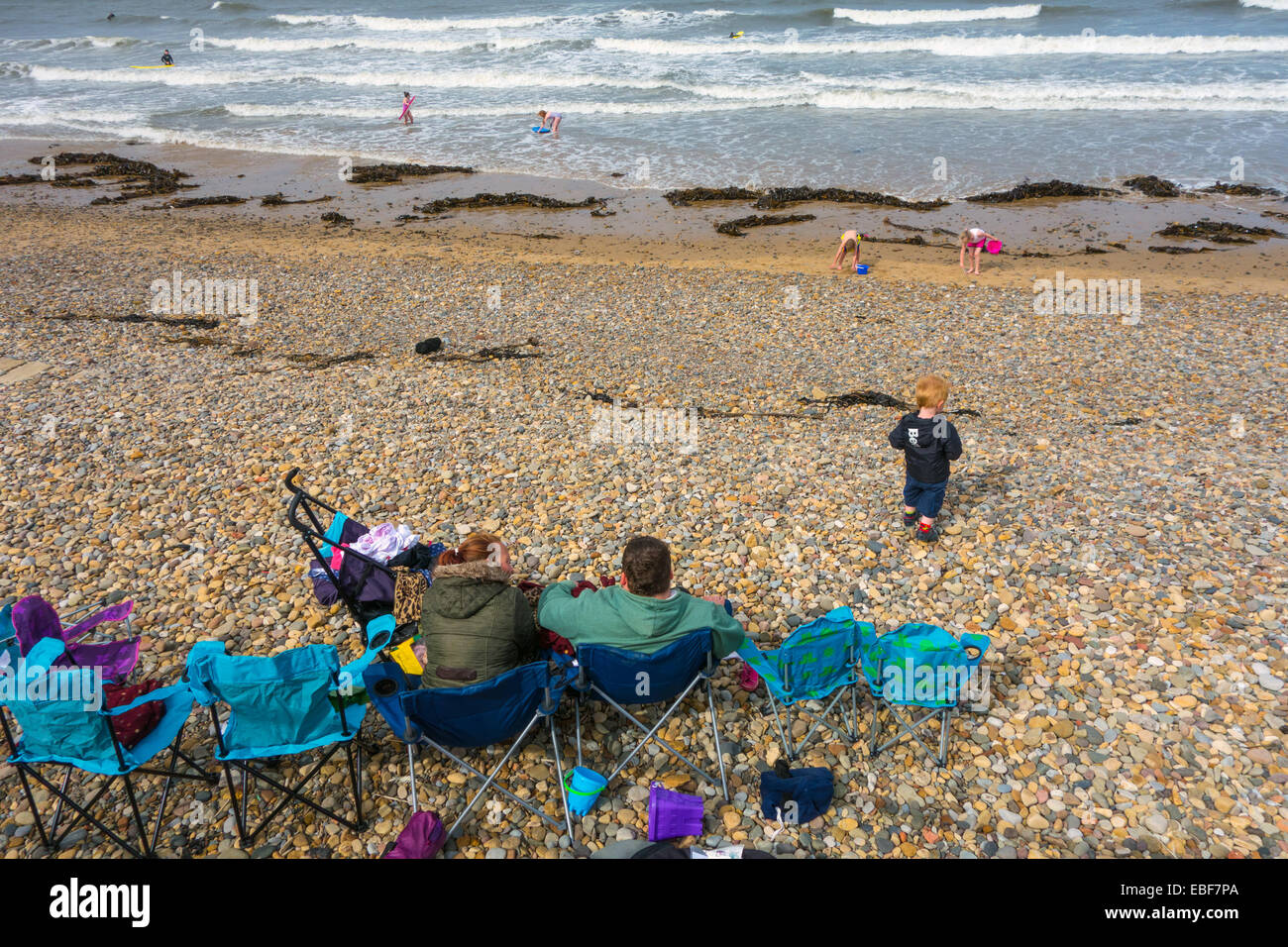 Family on pebbly beach parents and children holiday beach scene, Saltburn by the Sea, holiday resort Stock Photo
