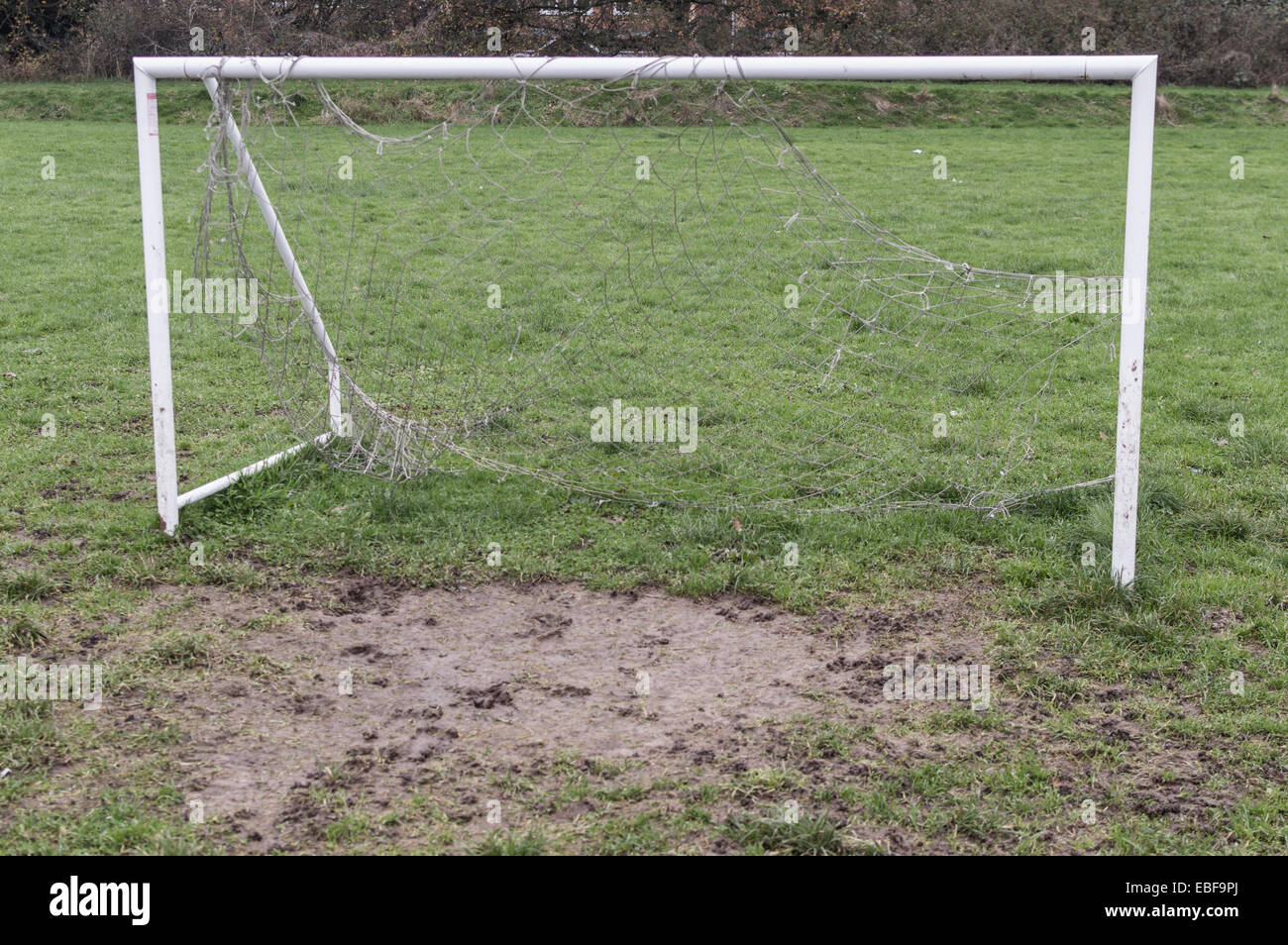 An empty five-a-side football goal with a net, on a muddy park field Stock Photo