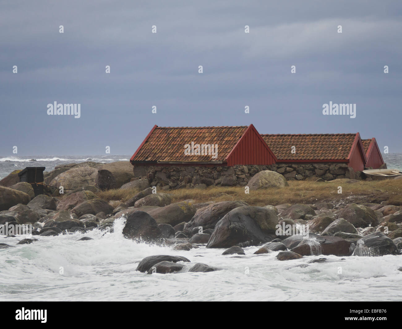Autumn or winter storms, Jaeren west coast of Norway near Stavanger waves breaking over stones, beach and boathouses Stock Photo