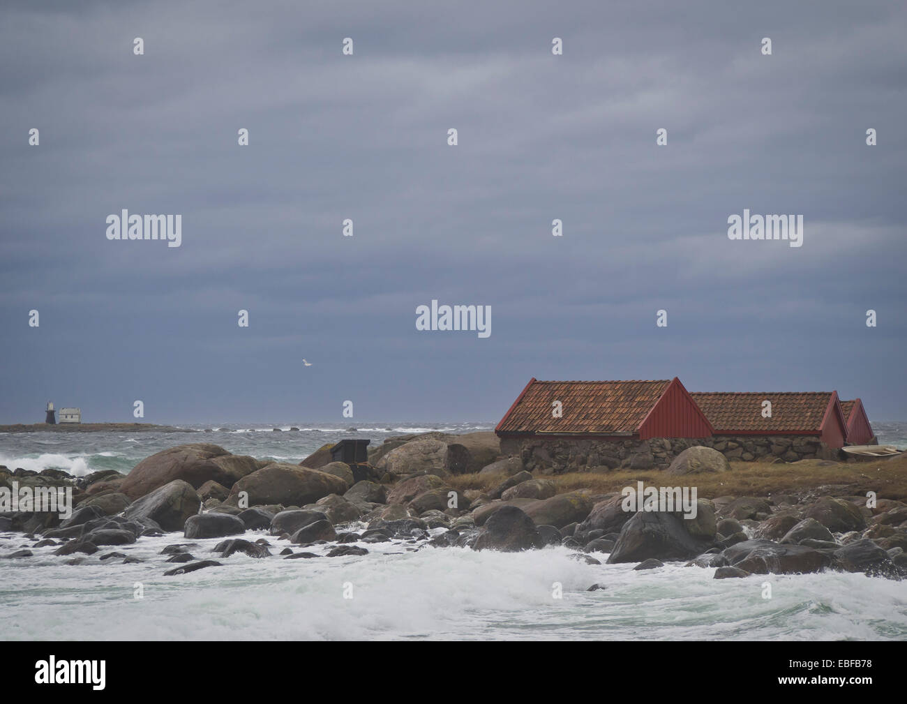 Autumn or winter storms, Jaeren west coast of Norway near Stavanger waves breaking over stones, beach, boathouses and lighthouse Stock Photo