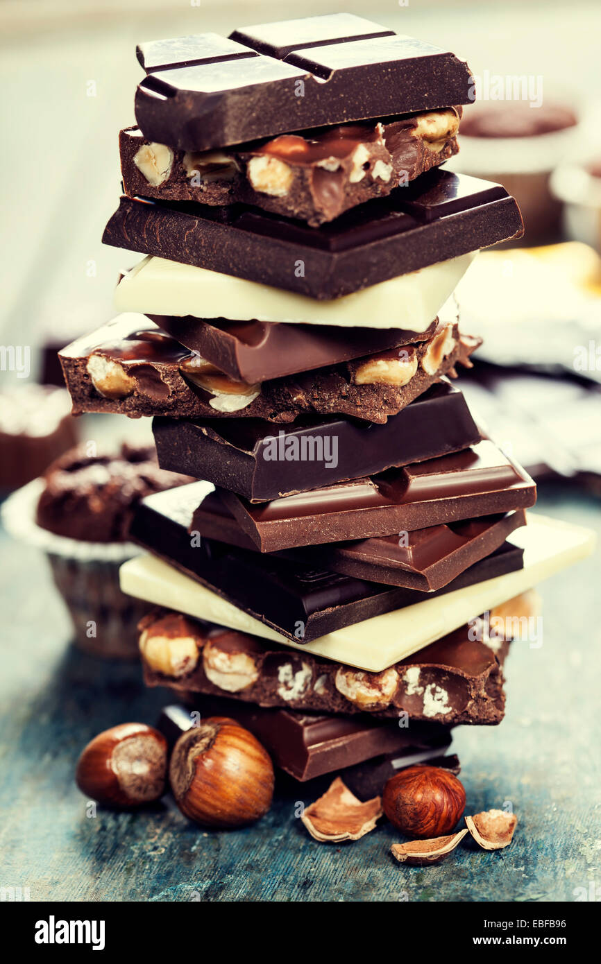 An assortment of  white, dark, and milk chocolate with nuts - on wooden board Stock Photo