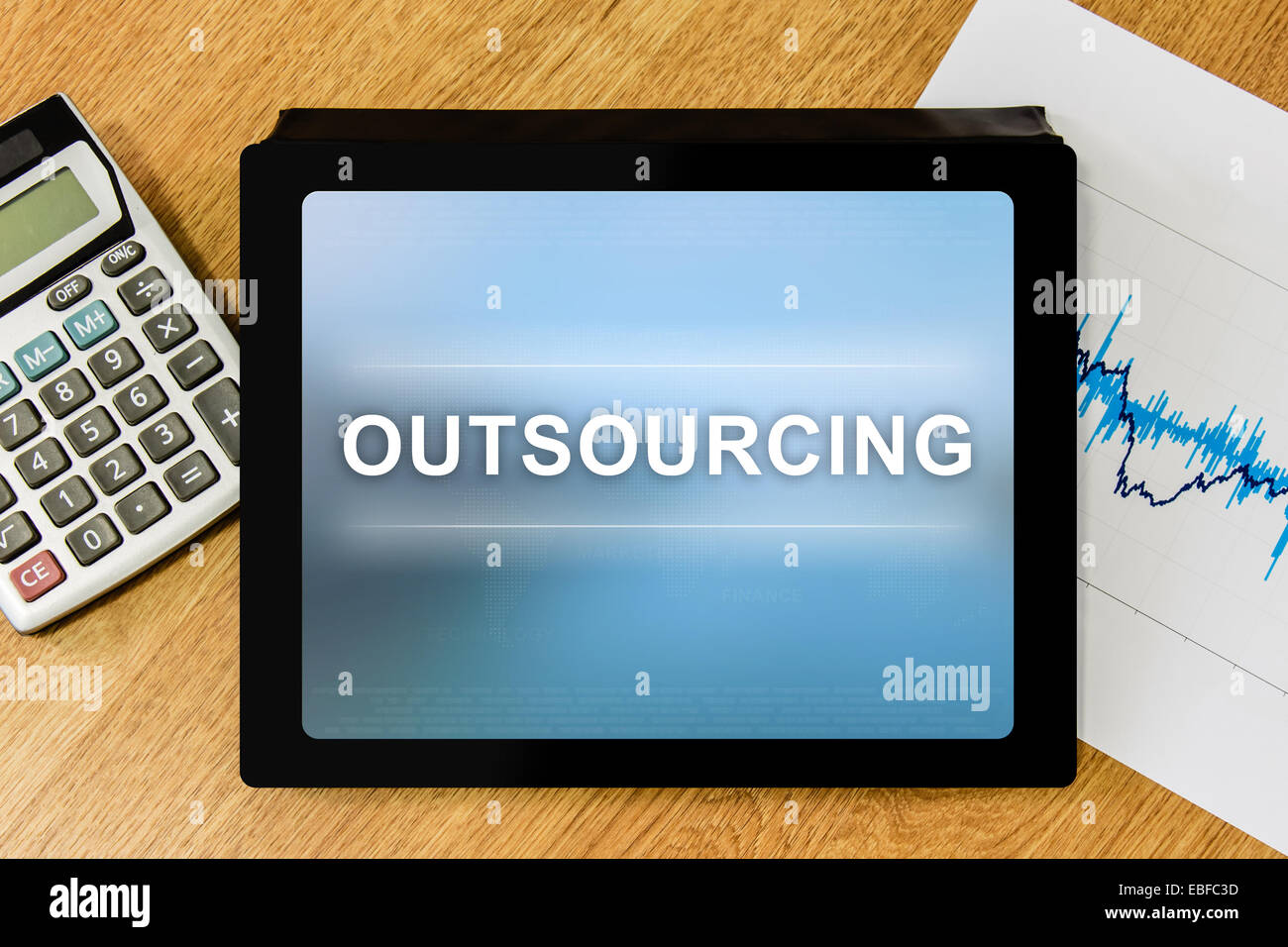 Outsourcing word on digital tablet with calculator and financial graph Stock Photo