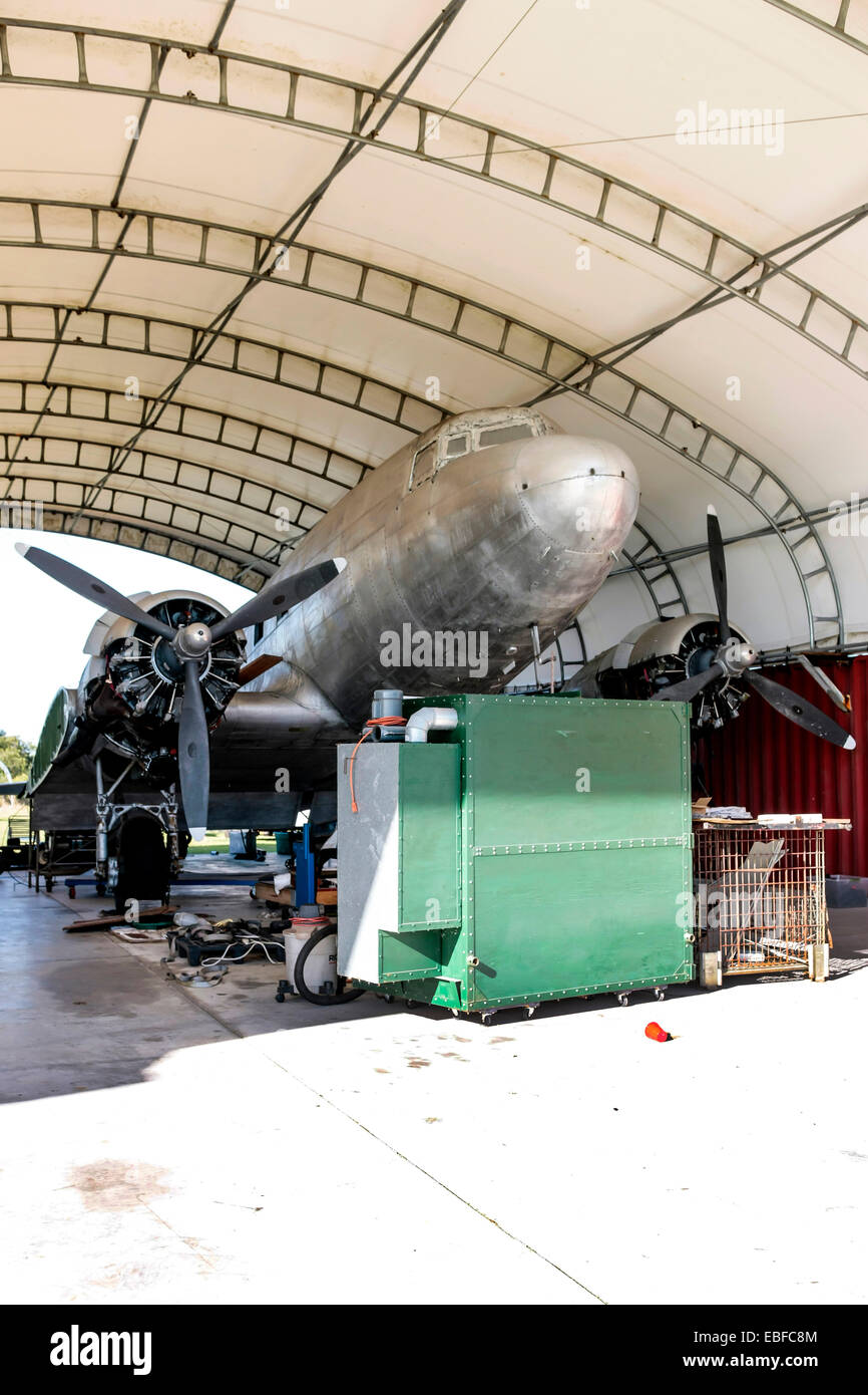 A Douglas DC-3 being restored under an open hangar in Florida Stock Photo