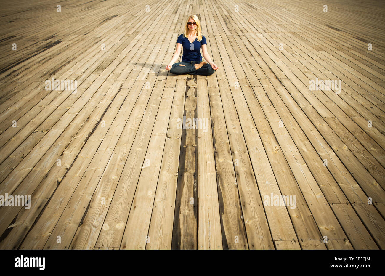 Young woman meditating sitting in lotus position on wooden floor Stock ...