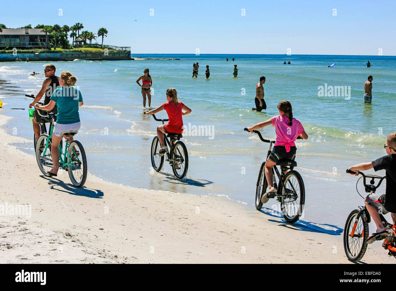 A familt riding beach cruiser bicycles along Crescent beach on Siesta