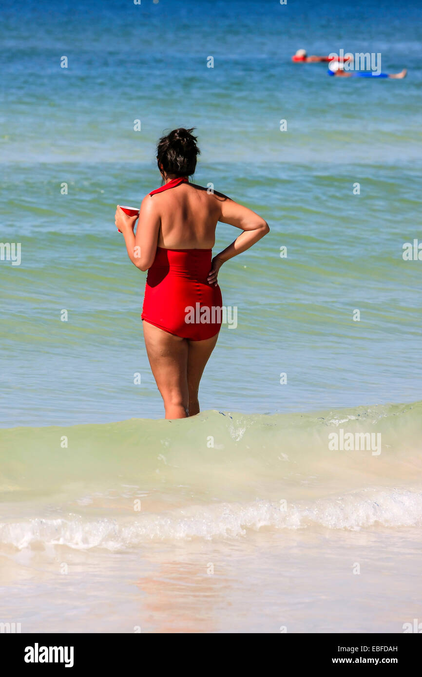 A woman dressed in a red bathing suit looks out to sea from Crescent