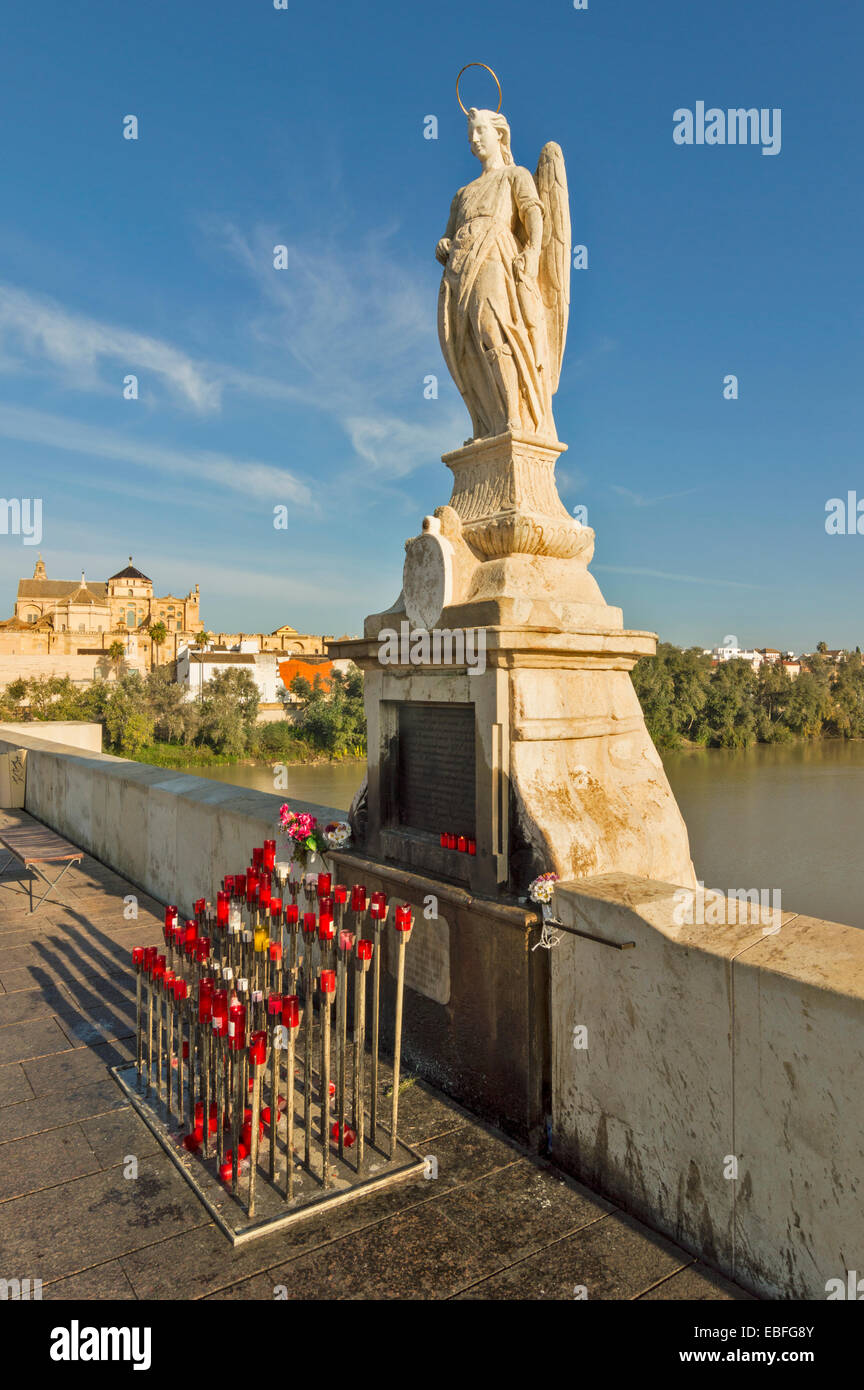 CORDOBA SPAIN A SHRINE WITH A STATUE OF ST RAPHAEL AND CANDLES ON THE ROMAN BRIDGE THE MOSQUE CATHEDRAL IN THE DISTANCE Stock Photo