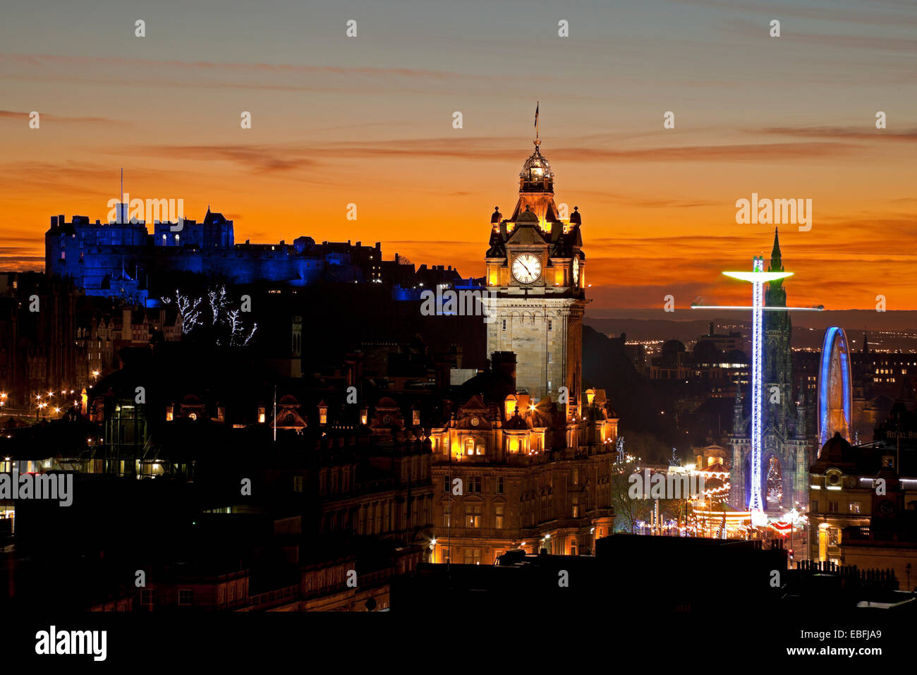 Edinburgh, Scotland, UK. 30th November, 2014. Edinburgh Castle and the city viewed from Calton Hill at sunset the castle is illuminated with blue lighting during St Andrew's Day celebrations, also showing the Big Wheel and Star Flyer rides situated beside the Scott Monument in Princes Street Gardens East. Stock Photo