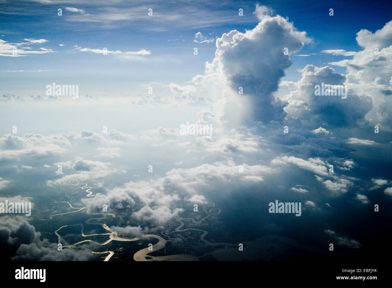 High altitude clouds, cumulus clouds, in color, dramatic photograph. Twisting rivers and streams below in surface. Stock Photo
