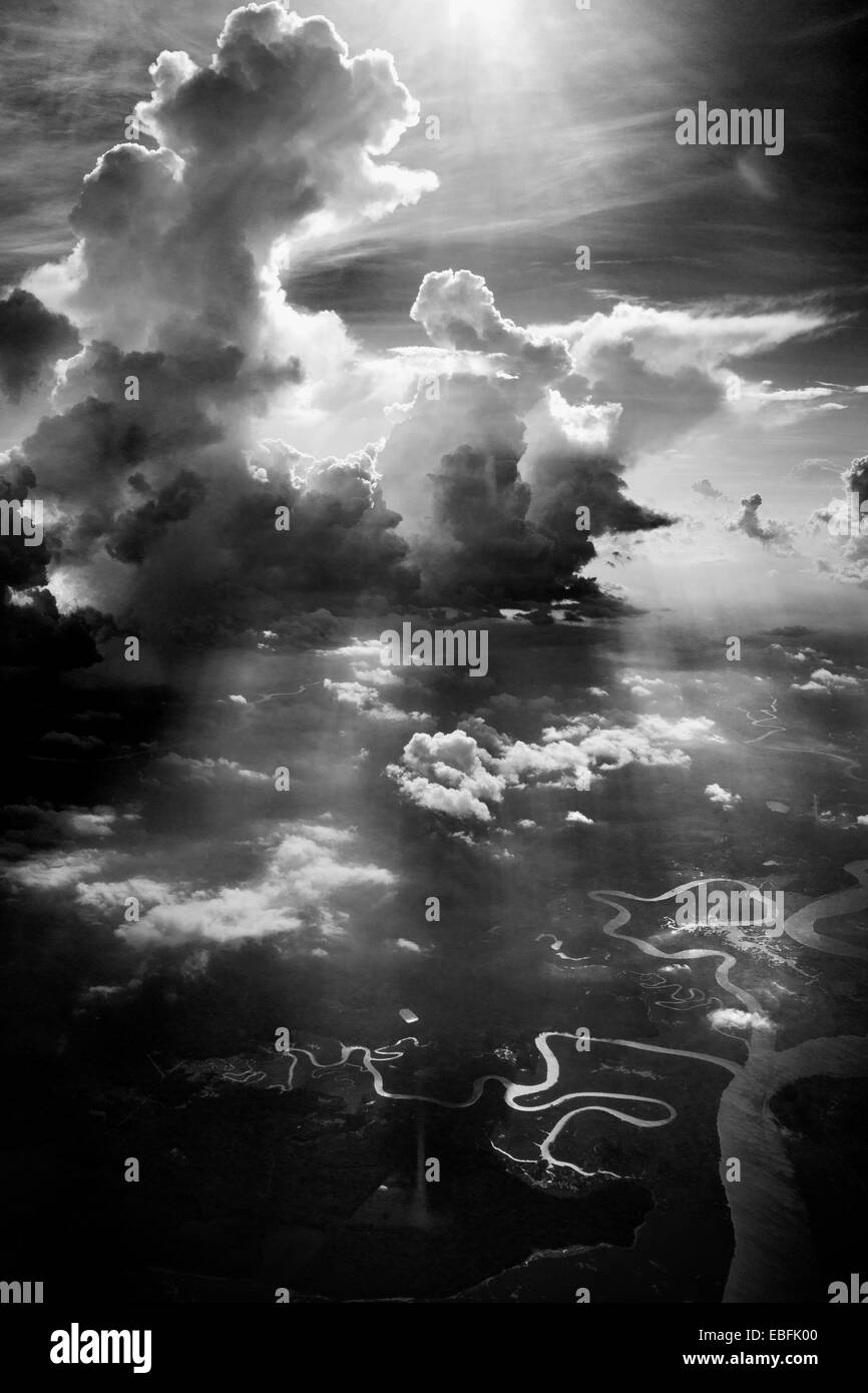 High altitude clouds, cumulus clouds, in black & white, dramatic photograph. Twisting rivers and streams below in surface. Stock Photo