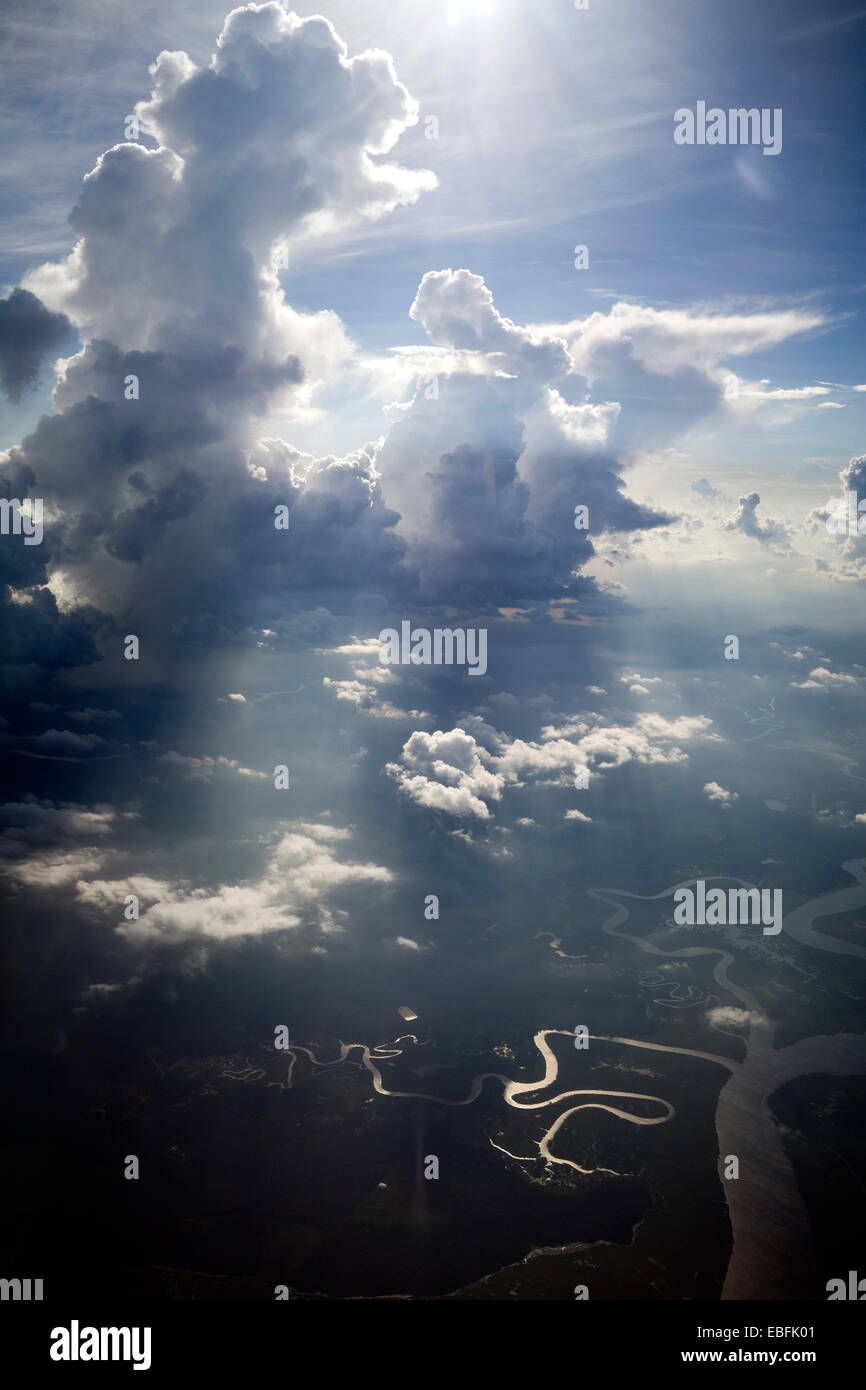 High altitude clouds, cumulus clouds, in color, dramatic photograph. Twisting rivers and streams below in surface. Stock Photo