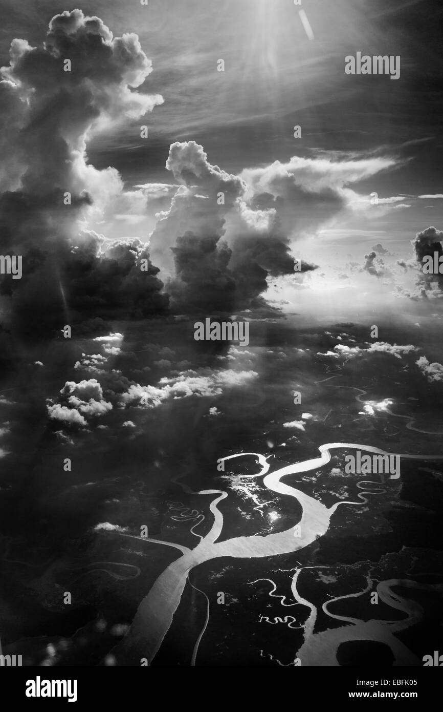 High altitude clouds, cumulus clouds, in black & white, dramatic photograph. Twisting rivers and streams below in surface. Stock Photo