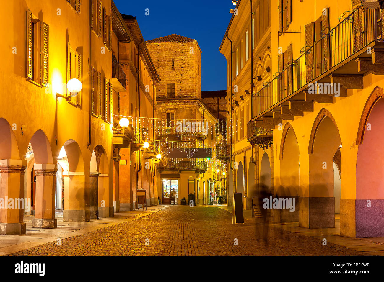 Silhouettes of people walking on evening streets of Alba in Piedmont ...