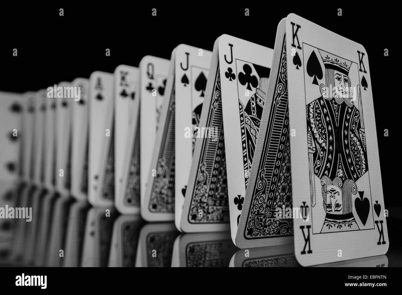 A set of playing cards in formation, reflecting onto the table below. Stock Photo