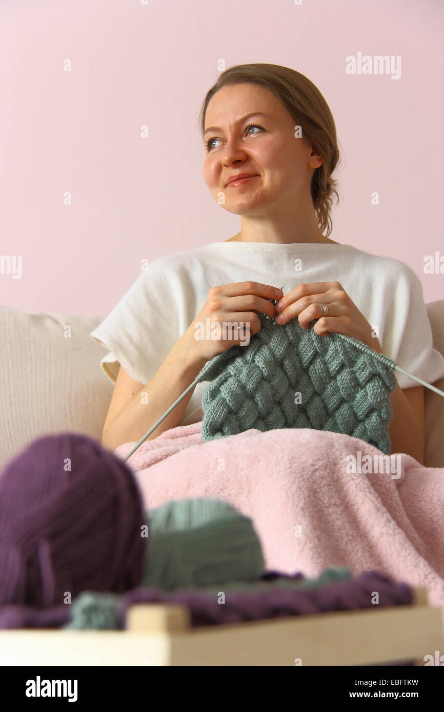 happy young woman knitting on sofa Stock Photo - Alamy