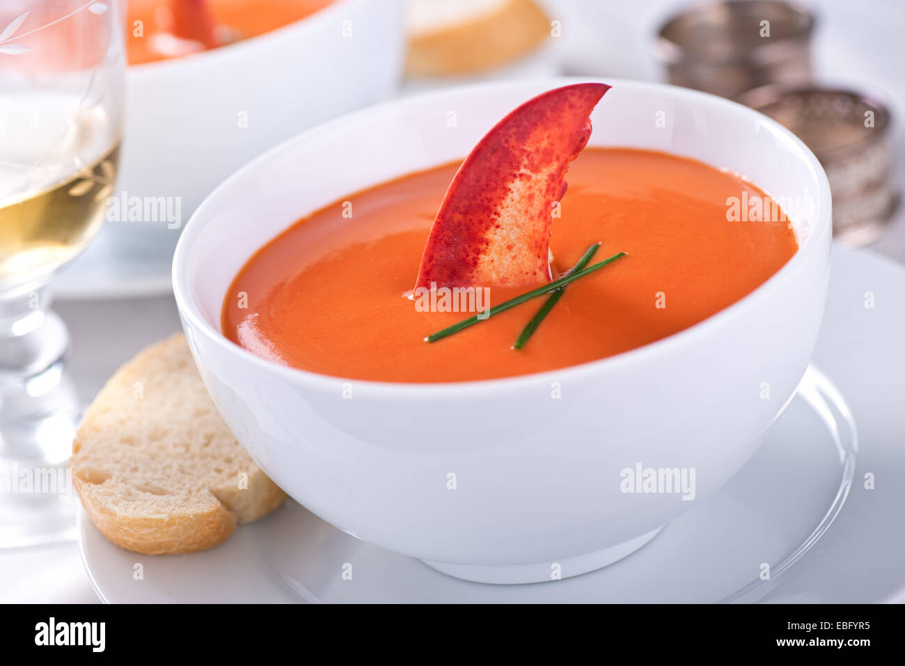 A bowl of creamy delicious lobster bisque garnished with chives and a