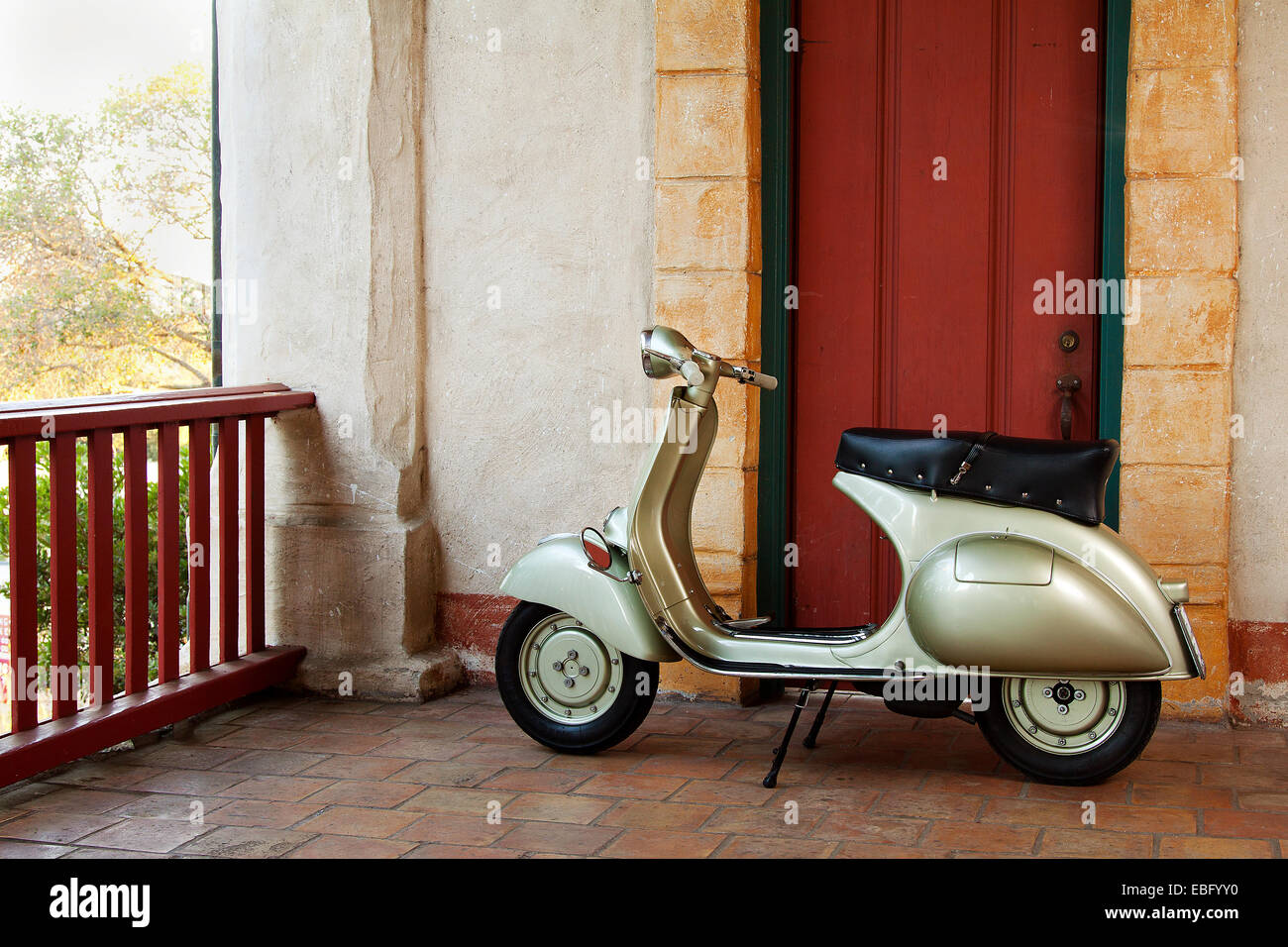 1958 green Vespa scooter infront of a red rustic door Stock Photo