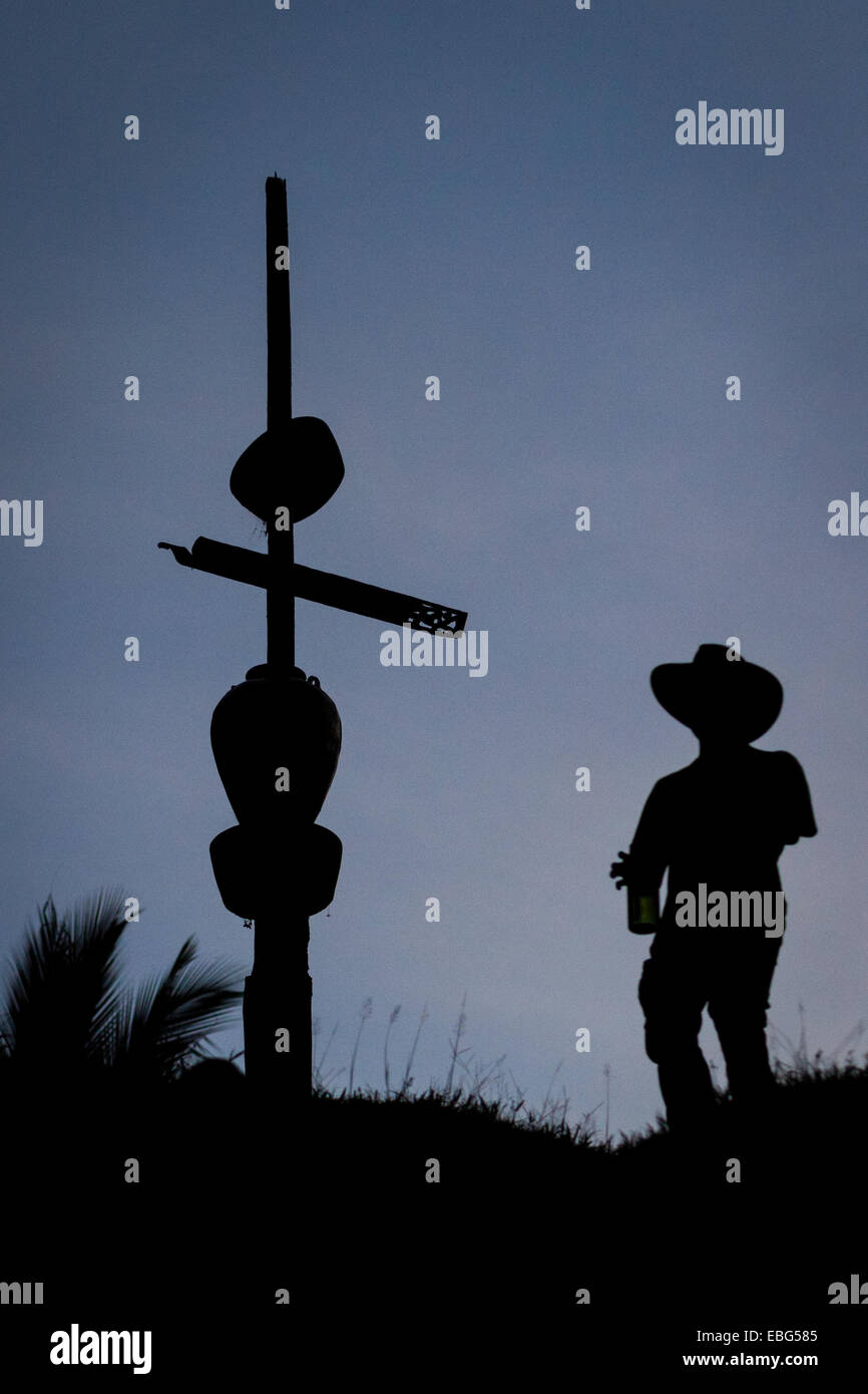 A facilitator of ecotourism wearing cowboy hat is silhouetted as he is walking past a totem pole in Nanga Raun, Kalis, Kapuas Hulu, Indonesia. Stock Photo