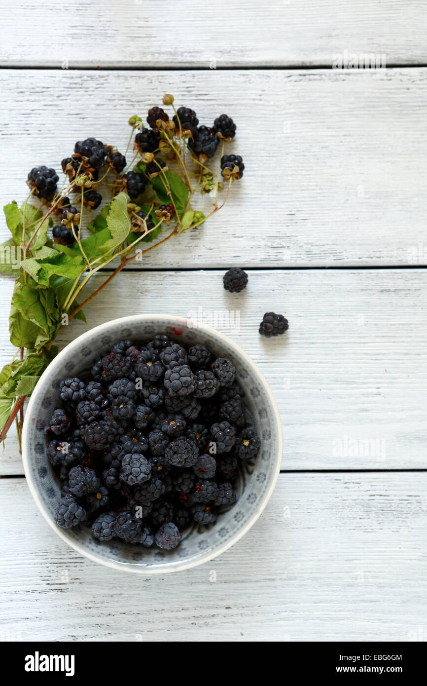 Forest blackberries in a bowl on wooden boards, top view Stock Photo