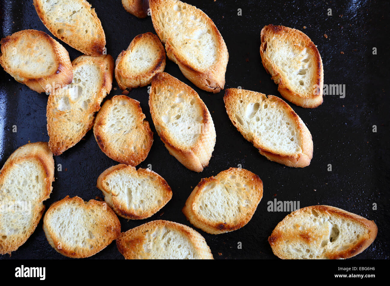 Crispy baked baguette slices on a baking tray, delicious food Stock
