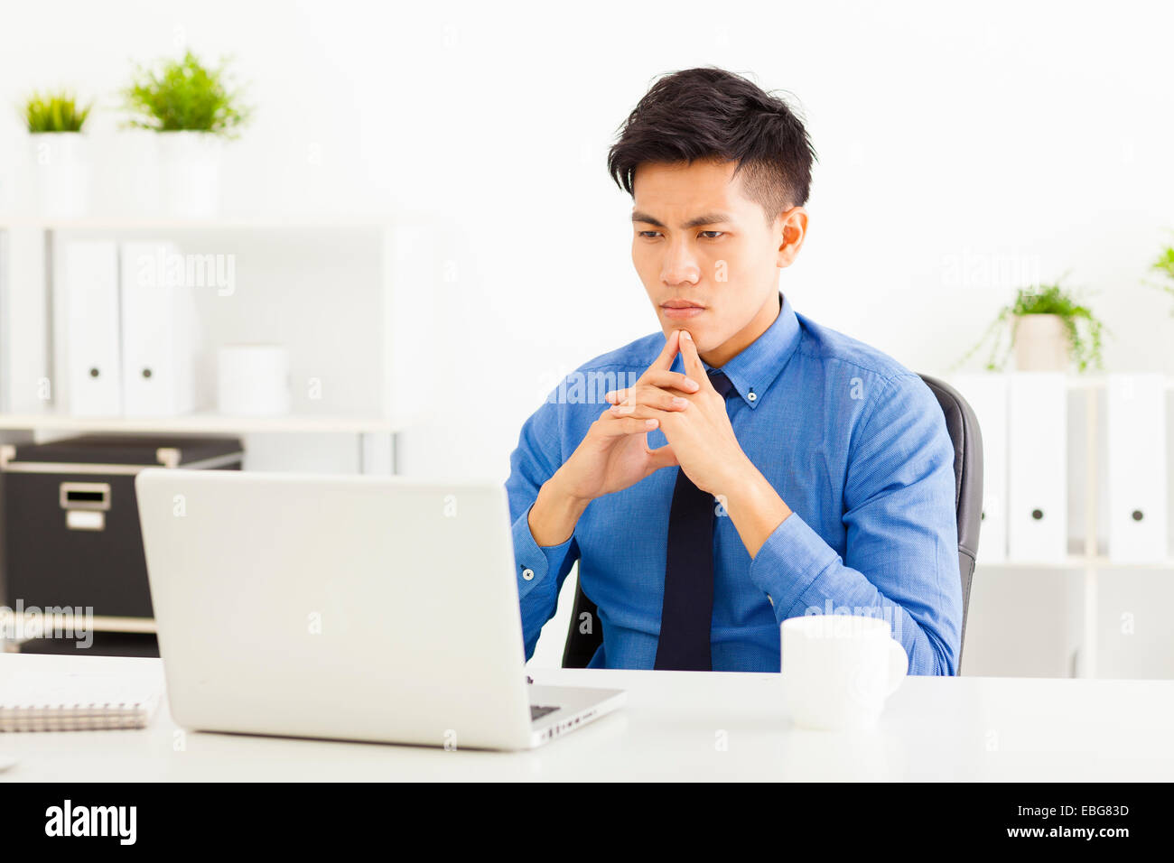 Young asian businessman watching laptop and thinking Stock Photo