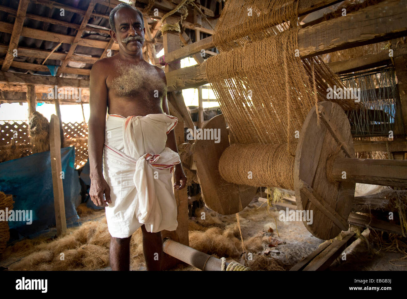 Man making ropes from coconut fibres in a small business, Vembanad lake, Kerala, India Stock Photo