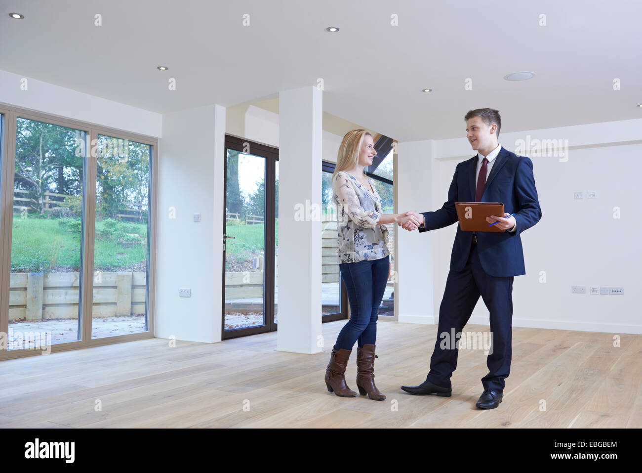Woman Shaking Hands With Estate Agent In New Home Stock Photo