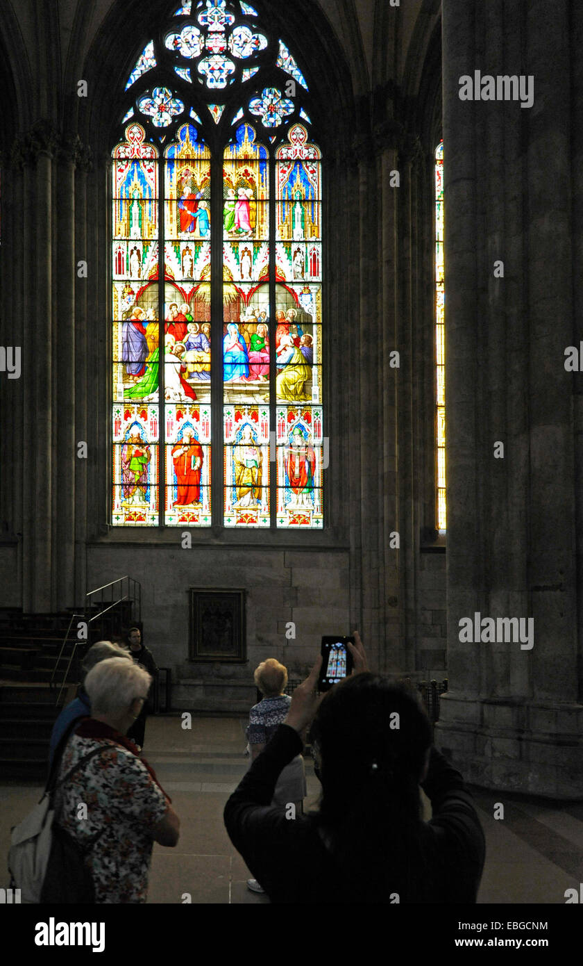 Woman photographing the cathedral windows 'taking down th Cross' with their smartphone in the cathedral of Cologne, NRW, Germany Stock Photo