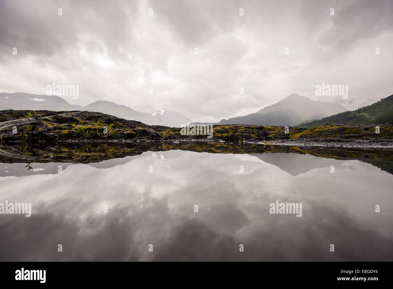 Mountain range reflected into still water near Seward Alaska Stock