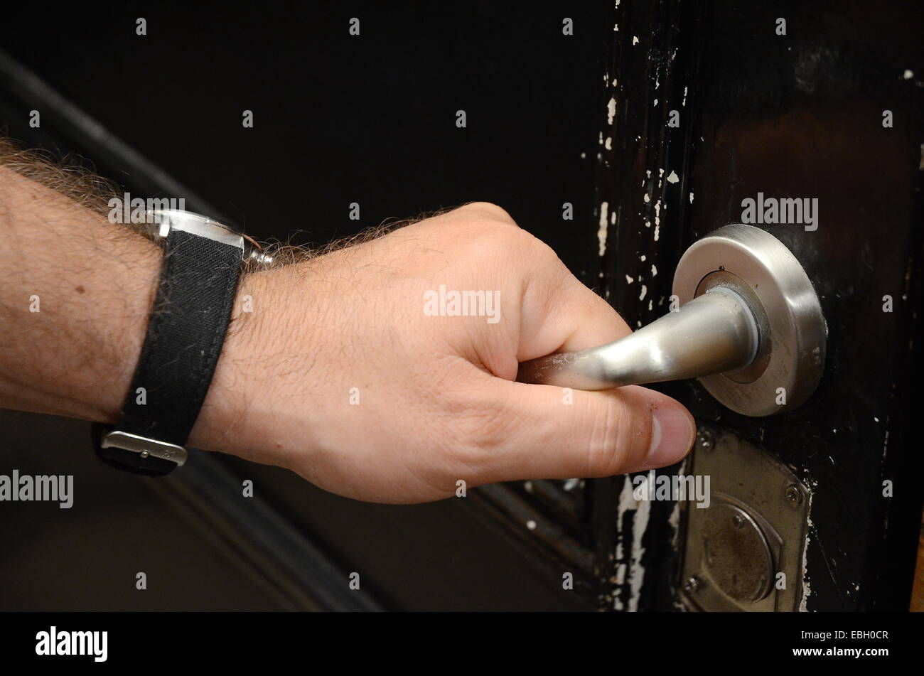 Close-up of masculine hand on doorknob opening a door Stock Photo