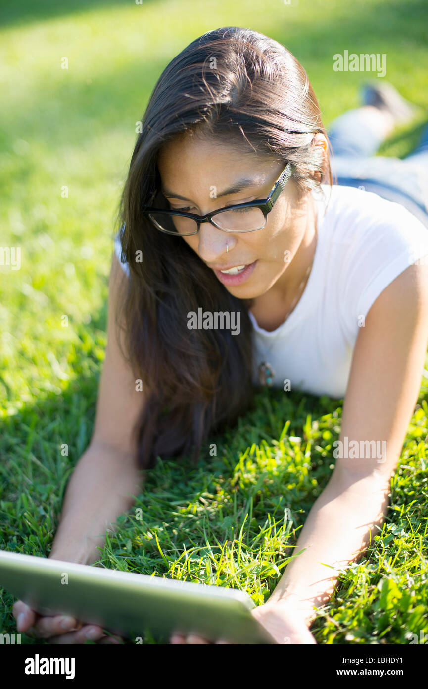 Young woman lying on grass using digital tablet Stock Photo - Alamy