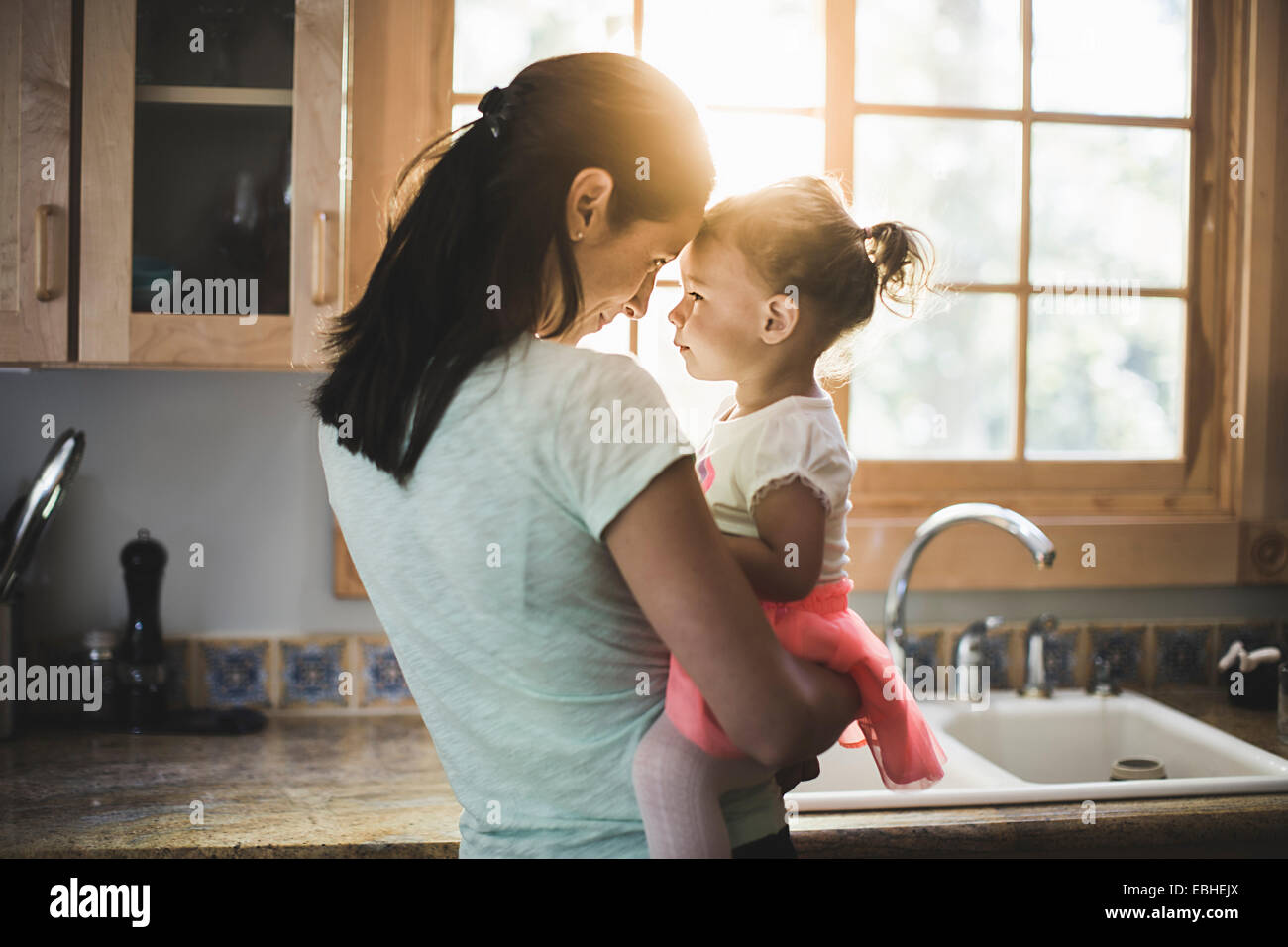 Mother and daughter playing in kitchen Stock Photo