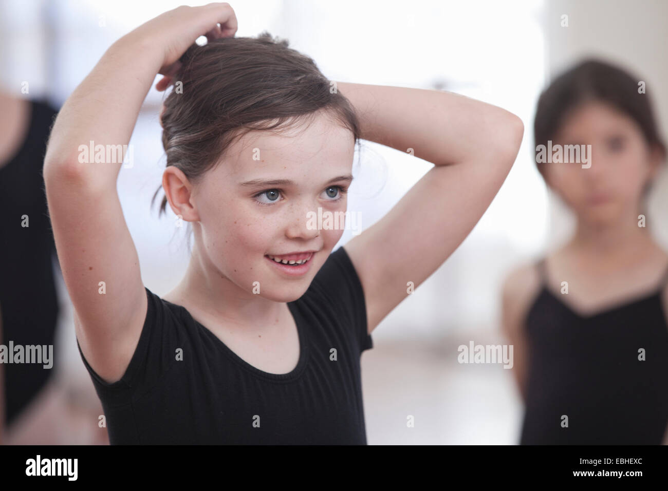 Girl pinning back her hair in ballet school Stock Photo