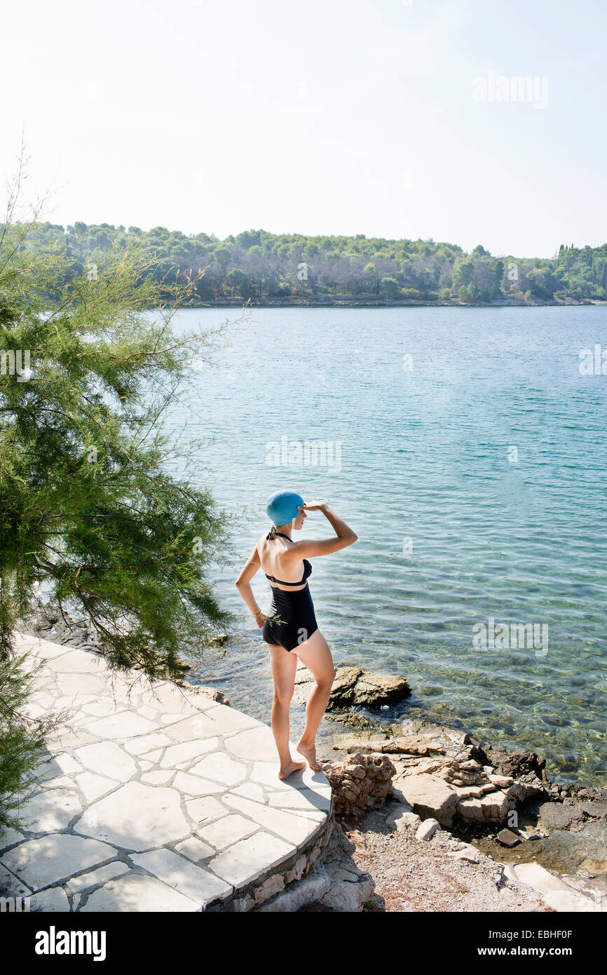 Rear view of young woman wearing swimming costume gazing out to sea, Milna, Brac, Croatia Stock Photo