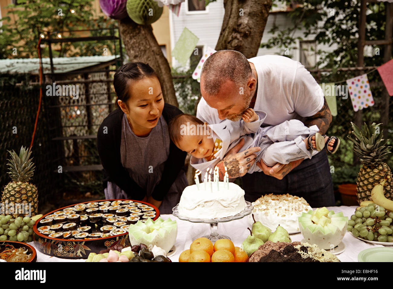 Parents and male toddler having birthday party in garden Stock Photo