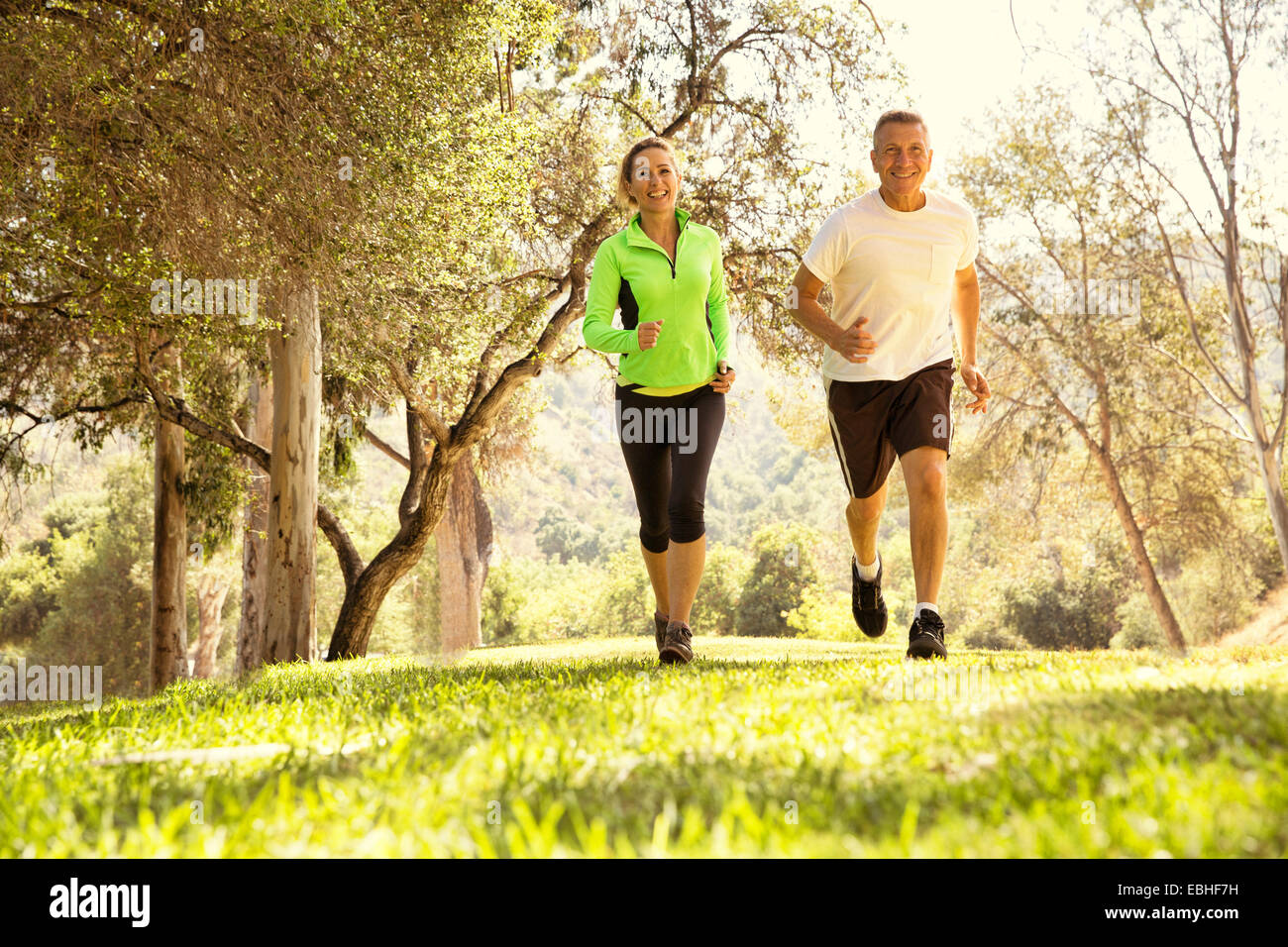 Mature couple running through park Stock Photo