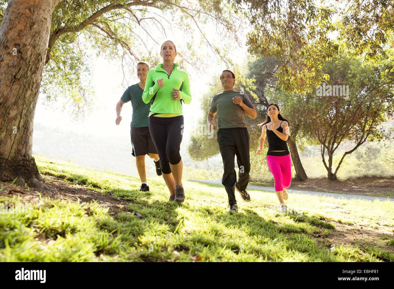 Four mature men and women running in park Stock Photo