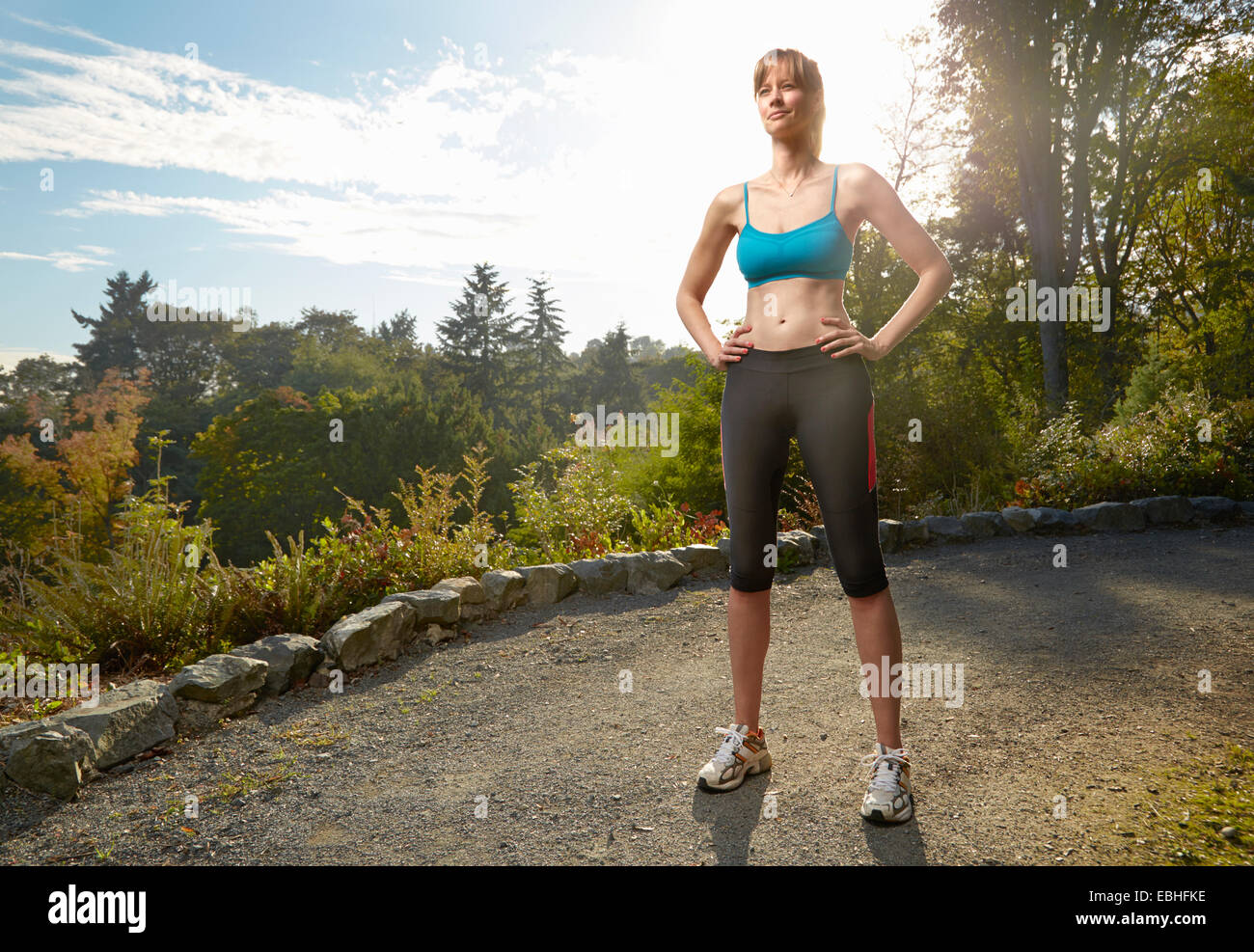Portrait of female runner with hands on hips in park Stock Photo