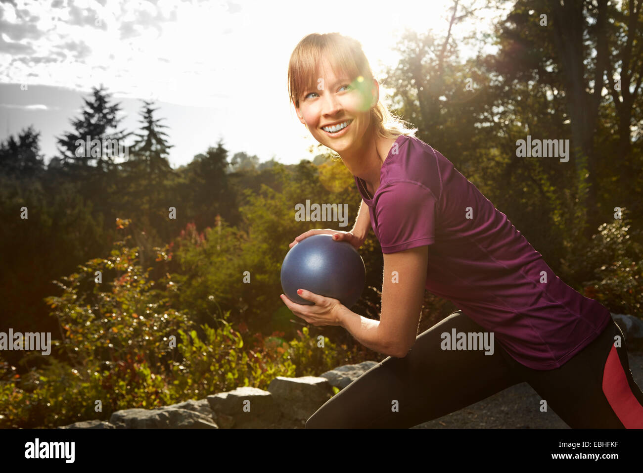 Mid adult woman using exercise ball in park Stock Photo