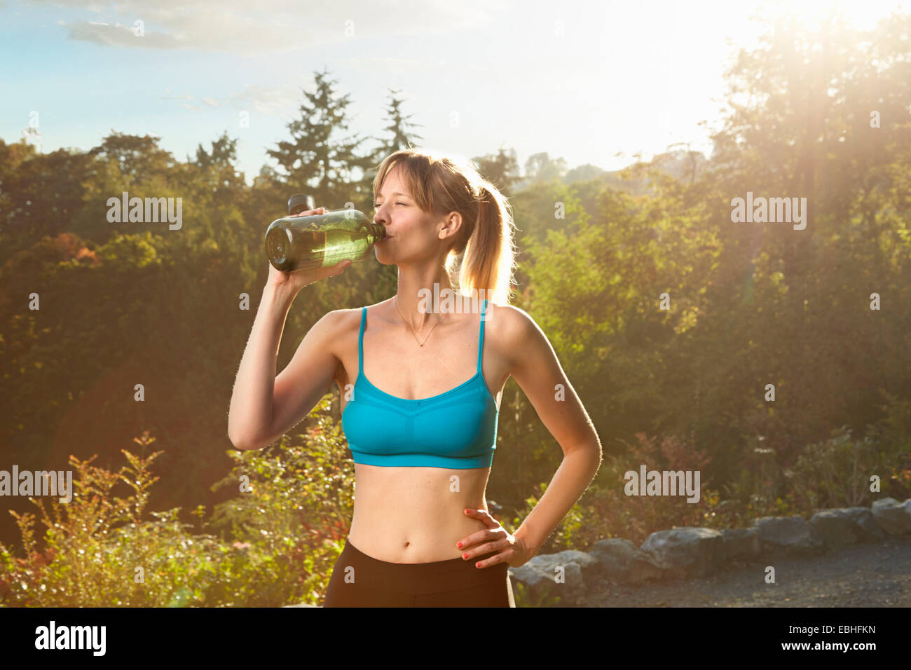 Mid adult female runner taking a water break in park Stock Photo