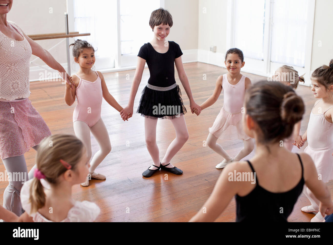 Children and teacher in a circle practicing ballet in ballet school Stock Photo