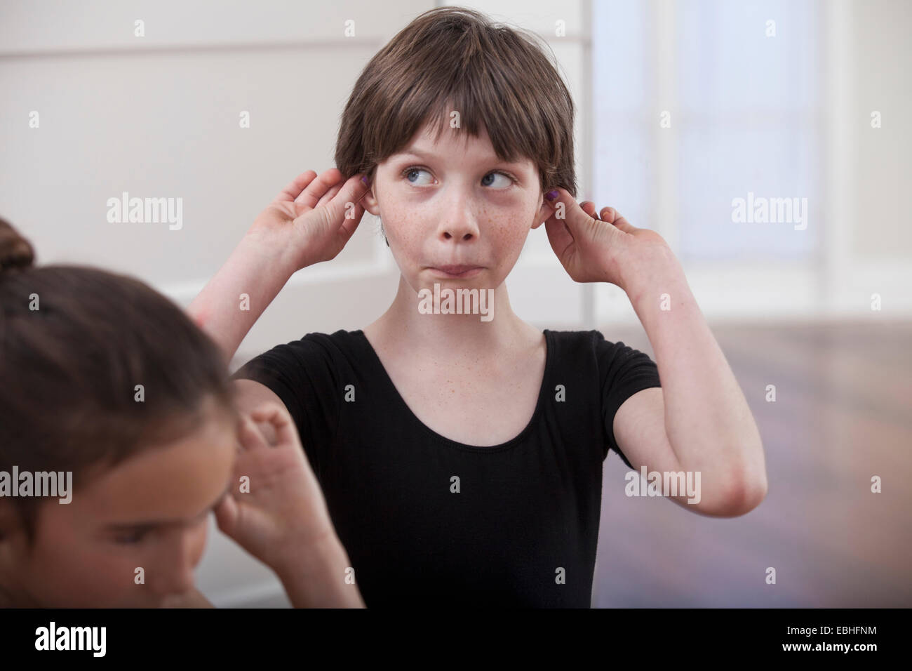 Girl with holding ears pulling a face in ballet school Stock Photo