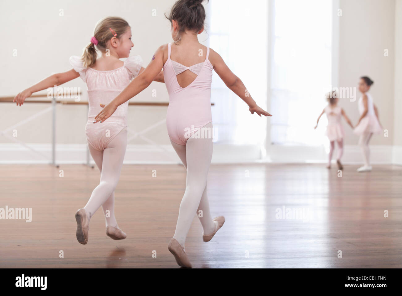 Rear view of girls practicing jump in ballet school Stock Photo