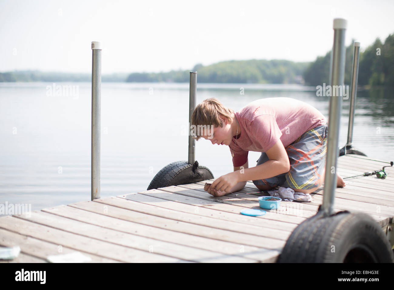Teenage boy preparing fishing bait on pier, Lake Superior, Gwinn, Michigan, USA Stock Photo